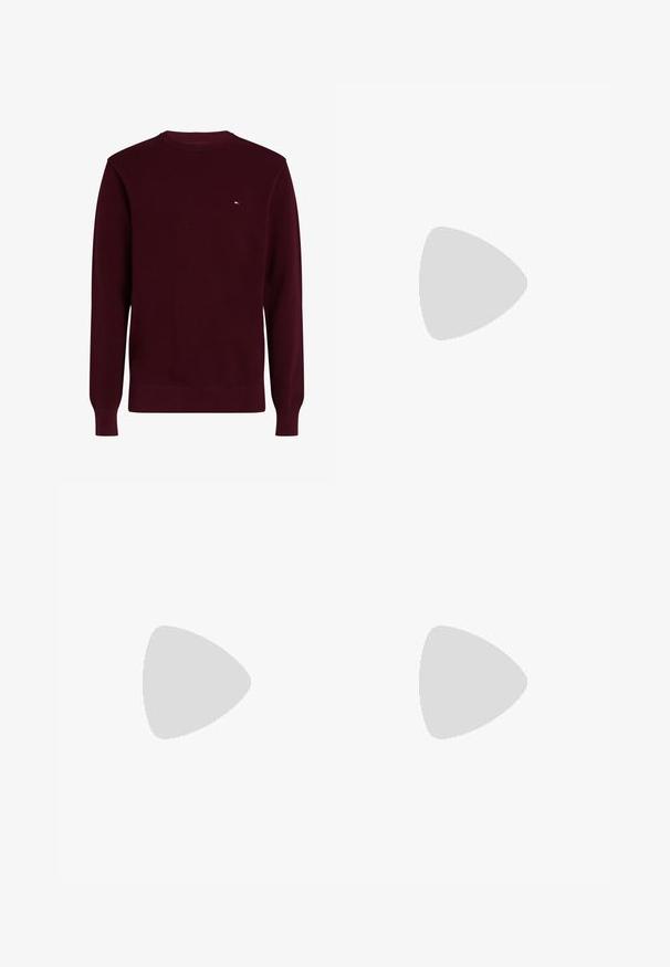 Donkerrode trui met ronde hals en klein rechthoekig logo op de linkerborst, lange mouwen en geribde boorden aan mouwen en zoom.; Witte button-up shirt gemaakt van katoen, met een klassieke kraag, lange mouwen en een klein CK-logo op de linkerborst. Glad oppervlak.; Zwarte spijkerbroeken van denim, met een slim fit, vijf-pocket ontwerp en een kleine rode en blauwe accent op de voorzak.; Zwarte leren herensloffen met een band over de bovenkant, getoond op een beige tapijt vlakbij een bruine moderne ronde tafel.