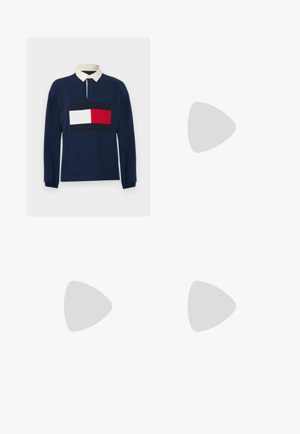 Marineblå langærmet rugbytrøje med hvid krave og stort Tommy Hilfiger-logo i rød, hvid og marineblå på brystet.; Skjorte med lange ærmer og knapper med røde, marineblå og hvide lodrette striber og et lille logo på brystet.; Lyseblå denimjeans med lige ben, fem lommer, kontrasttråd og en let slidt finish. Knap- og lynlåslukning.; Sort læder loafersko svæver over beige tæppe med buet ravbrun møbelgenstand i baggrunden.