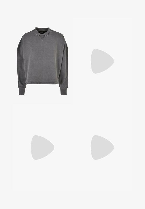 Grijze oversized sweatshirt van katoen, met een ronde hals, lange mouwen, ribgebreide manchetten en een subtiele textuur.; Witte korte mouwen t-shirt van zachte katoen. Heeft een ronde halslijn en een subtiele logo detail op de linkerborst. Rechte pasvorm.; Losse lichtbruine sweatpants met elastische tailleband, zijzakken en een subtiel "PEGADOR"-logo op de rechterdij.; Witte Nike Cortez sneaker met zwart Swoosh-logo, beige zool en veters, geplaatst boven grijze betonnen trappen en grond.
