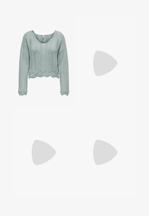 Pull court vert clair en tissu tricoté, avec un col en V, des manches longues, et un ourlet ondulé. Présente un motif ajouré dans tout le vêtement.; Shorts en denim jaunes avec une taille haute et une coupe décontractée, ornés de petits clous en argent éparpillés sur le devant pour un effet de détail.; Jambes portant des leggings côtelés foncés associés à des ballerines noires avec de petits détails en nœud sur fond blanc.; Petit sac à main noir brillant avec deux longues anses et des détails à cordon sur les côtés sur un fond clair uni.