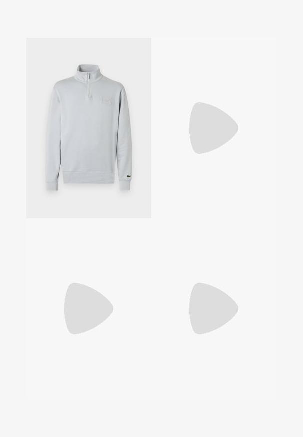 Sweatshirt gris clair à col demi-zippé, poignets côtelés et logo Lacoste texturé sur la poitrine, fabriqué en tissu doux.; T-shirt blanc à manches courtes avec texte noir "LACOSTE", un grand imprimé crocodile noir et texte "PARIS" en dessous sur le devant.; Pantalon de sport noir avec poches latérales, ceinture élastique, fines bandes latérales et petit logo crocodile vert sur la hanche droite.; Baskets noires en matériau synthétique lisse, avec un design bas, bout rond, système de laçage à l'avant, logo en relief et semelle texturée.