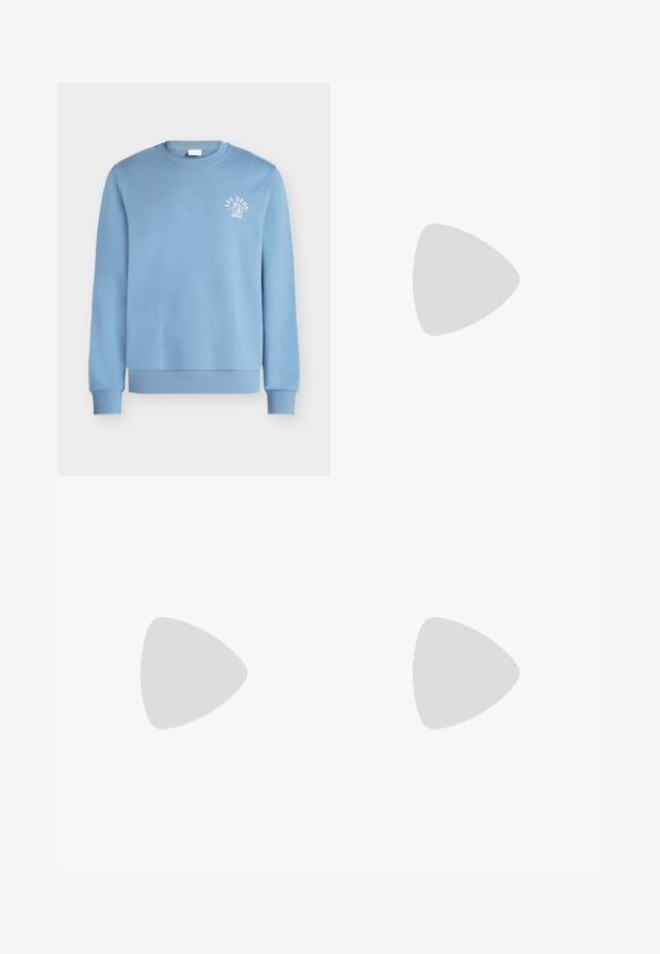 Sweat-shirt bleu clair à col rond avec poignets et ourlet côtelés, avec un petit texte blanc "LES DEUX" et un dessin sur la poitrine gauche.; Chemise en tissu vert clair texturé avec un col classique, des manches longues et une fermeture frontale à boutons argentés.; Pantalon beige droit avec fermeture par bouton et zip, passants pour ceinture et poches latérales sur fond uni.; Baskets beiges en daim avec semelle en gomme, design à lacets, flottant à l'intérieur sur un sol en béton poli près d'un mur en blocs de verre.