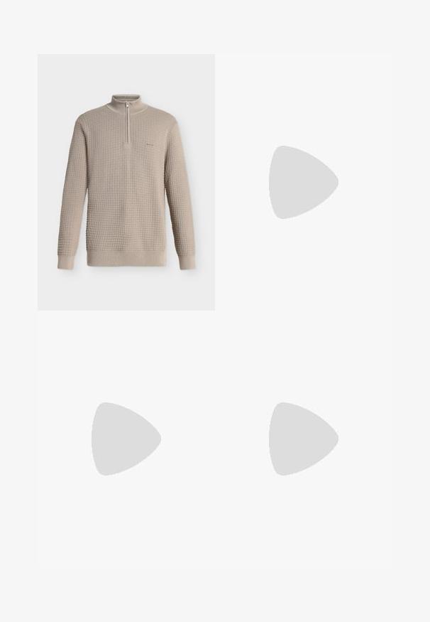 Pull beige en maille gaufrée, manches longues, col montant à demi-fermeture éclair, poignets et ourlet côtelés, présenté sur fond blanc.; Jean droit bleu clair avec un effet délavé, design à cinq poches, accessoires métalliques et fermeture éclair. Texture en denim lisse.; Chaussure mocassin en cuir noir présentée en suspension au-dessus d'un tapis beige tissé, avec une table en bois et des livres empilés dans un salon doucement éclairé.; Ceinture en cuir noir roulée avec une boucle métallique argentée rectangulaire sur un fond clair uni.