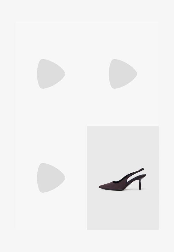 Femme portant une combinaison cache-cœur plissée couleur prune à manches courtes et des talons noirs, debout devant un fond clair uni.; Chaussure à talon slingback en tissu violet foncé. Design à bout pointu, côtés ouverts, et talon mince de forme carrée. Texture lisse.; Sac à main bordeaux en matériau brillant, de forme rectangulaire, avec deux anses et des accents légèrement courbés à l'avant.; Boucles d’oreilles créoles en métal argenté avec une surface lisse légèrement incurvée et des fermoirs à clapet sur un fond blanc uni.