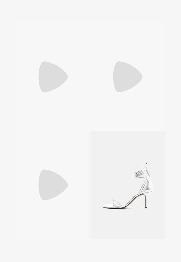 Glitrende sølvfarvet jumpsuit med lange ærmer, dyb V-hals og indpakningsdesign, der har et bånd i taljen og bred benåbning.; Sølv højhælede sandal med tynde stropper, ankelrem og slank stiletthæl på en ensfarvet hvid baggrund.; Lille sølvfarvet metallisk clutch-pung med rundet, rynket design og lukning med to sølvkugler.; Sølvøreringe med forlængede ovale led, der har en poleret overflade og en struktureret dråpevedhæng. Enkel design med glatte kanter.
