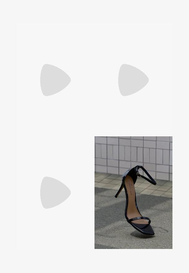 Sort langærmet bodystocking med indpakningsdesign, lavet af glat stof. Har en dyb udskæring og tætsiddende silhuet.; Sort laklæder sandal med høje hæle, ankelrem, guldbeslag og spids tå, placeret oprejst på en flisebelagt og asfalt belægning.; Lille flettet koralfarvet håndtaske med en knyttet hank og en rød lynlåstræk på siden, vist mod en hvid baggrund.; Sølv kædeøreringe med forlænget design, der har en delikat kæde og lige, tynde pendanter i enderne. Glat tekstur.