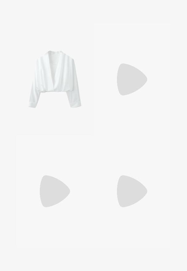 Blouse courte blanche à manches longues, col en V profond et coupe ample sur fond uni.; Pantalon formel noir droit avec pli devant, poches latérales et passants de ceinture, présenté sur fond blanc.; Ballerine en cuir beige avec un bout rond, détail en nœud et une bride de cheville avec une boucle en argent et des fermetures à pression. Semelle plate.; Sac à main rectangulaire noir avec de longues doubles poignées et des clous ronds en argent régulièrement espacés sur sa surface.