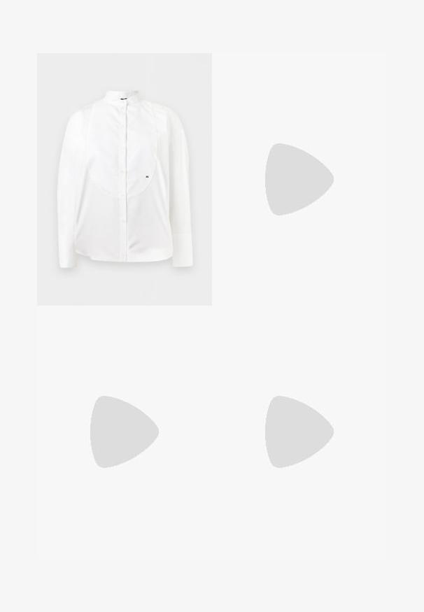 Chemise blanche à manches longues boutonnée avec col officier, plastron texturé et petit logo brodé "AX" sur le côté droit.; Pantalon marron foncé droit avec passants de ceinture et plis à l'avant, présenté à plat sur fond blanc.; Mocassins à imprimé léopard marron et noir, semelle épaisse en caoutchouc beige, et lacets marron, posés sur un tapis beige devant un canapé beige.; Sac à bandoulière en cuir bordeaux foncé avec fermeture à rabat et une fine sangle réglable, présenté sur un fond clair uni.
