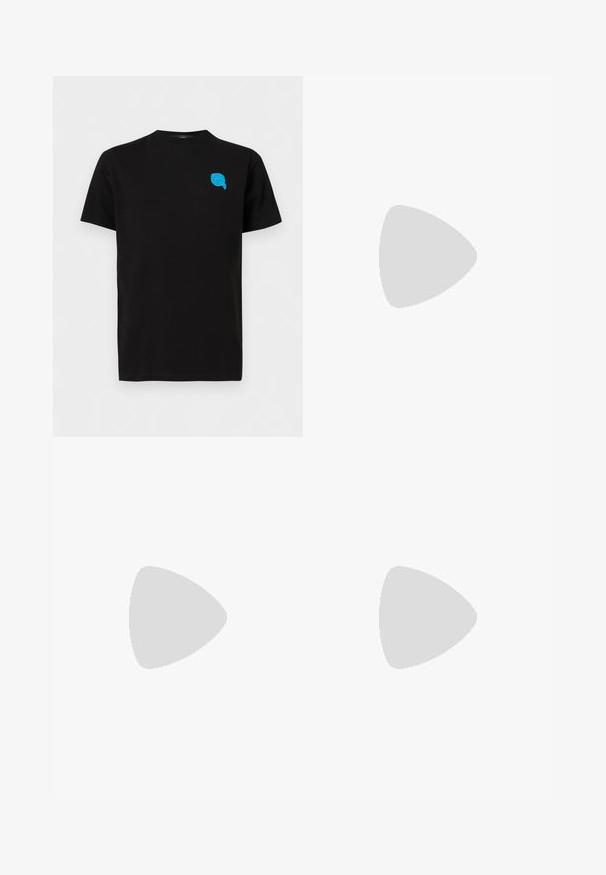 Camiseta negra de manga corta con un pequeño gráfico azul de una cara con gafas de sol y un pañuelo en la cabeza en la parte superior izquierda del pecho.; Jeans de mezclilla azul con un diseño de pierna recta, que cuentan con parches en contraste, dos bolsillos frontales y un detalle de lazo visible en el lado.; Mocasín de cuero negro con una placa metálica de marca apoyado cerca de una mesa redonda marrón sobre un suelo alfombrado beige.; Bolsa bandolera negra hecha de un tejido duradero, con dos bolsillos frontales con cremallera, una correa ajustable y un parche con el logo.
