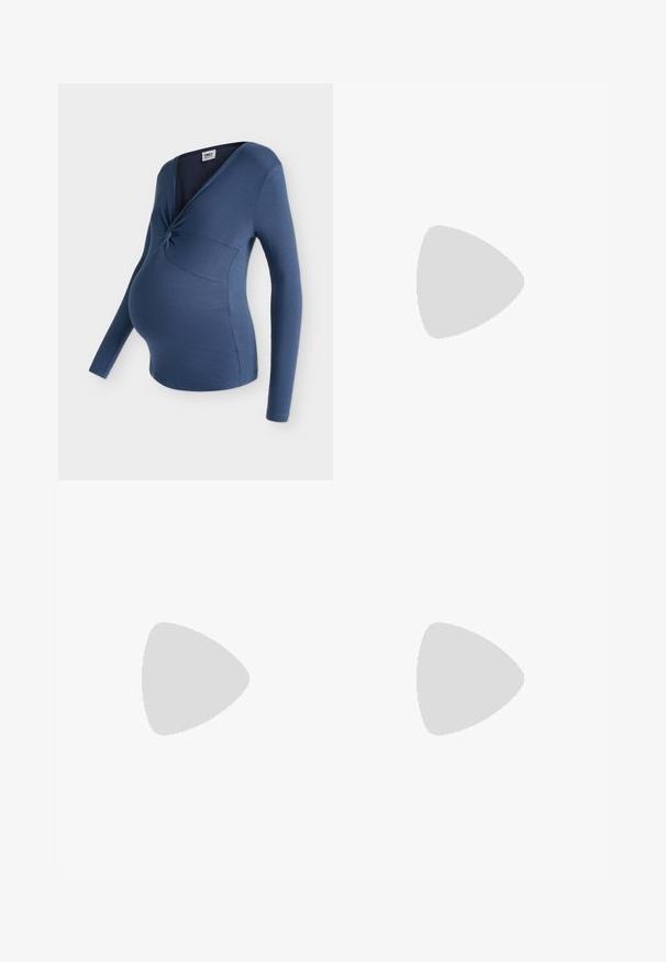 Haut de maternité bleu côtelé à manches longues avec un détail de nœud torsadé au niveau de la poitrine et un col en style cache-cœur.; Pantalons de maternité noirs avec une ceinture large et extensible, ornée d'un nœud. Fabriqués en tissu doux, ils présentent une coupe ample et des jambes larges.; Jambes portant des leggings côtelés foncés associés à des ballerines noires avec de petits détails en nœud sur fond blanc.; Sac à main en cuir tressé marron foncé avec poignée courbée, garniture blanche, fermeture éclair argentée et bandoulière large en tissu amovible sur fond uni.