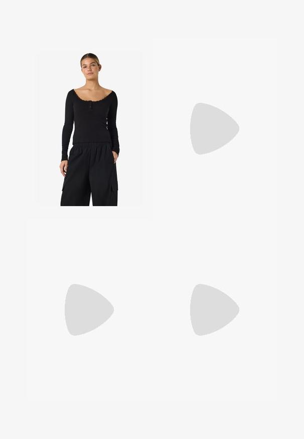 Vrouw draagt een zwarte ribgebreide top met lange mouwen, kantafwerking en knopen, gecombineerd met losse zwarte cargobroeken met zakken.; Zwarte wijde cropped broek met riemlussen en een hoge taille, weergegeven tegen een effen lichtgrijze achtergrond.; Zwarte leren veterschoenen met chunky zolen, zijrits en metalen oogjes. Gladde afwerking met variërende textuur op de schacht.; Bruine suède riem met zilveren ovale gesp en metalen oogjes, opgerold op een witte achtergrond.