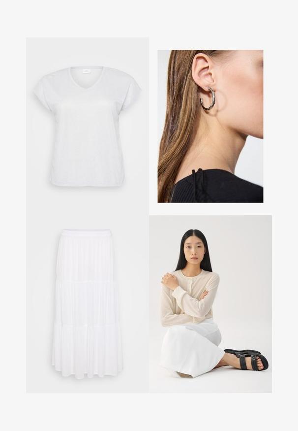 Witte korte mouwen V-hals T-shirt met een subtiele glanstextuur, met een ontspannen pasvorm en zonder zichtbare patronen of accenten.; Witte gelaagde maxi-rok van lichtgewicht stof, met een elastische tailleband en een vloeiende textuur met subtiele plooidetails.; Lichtbeige lange mouw blouse met knoopjes, gecombineerd met een witte rok; model draagt zwarte sandaaltjes met bandjes en zit met gekruiste armen.; Zilveren oorbel met een gepolijste afwerking, met kleine gouden accentdetails en een ronde vorm, gedragen op de oorlel.