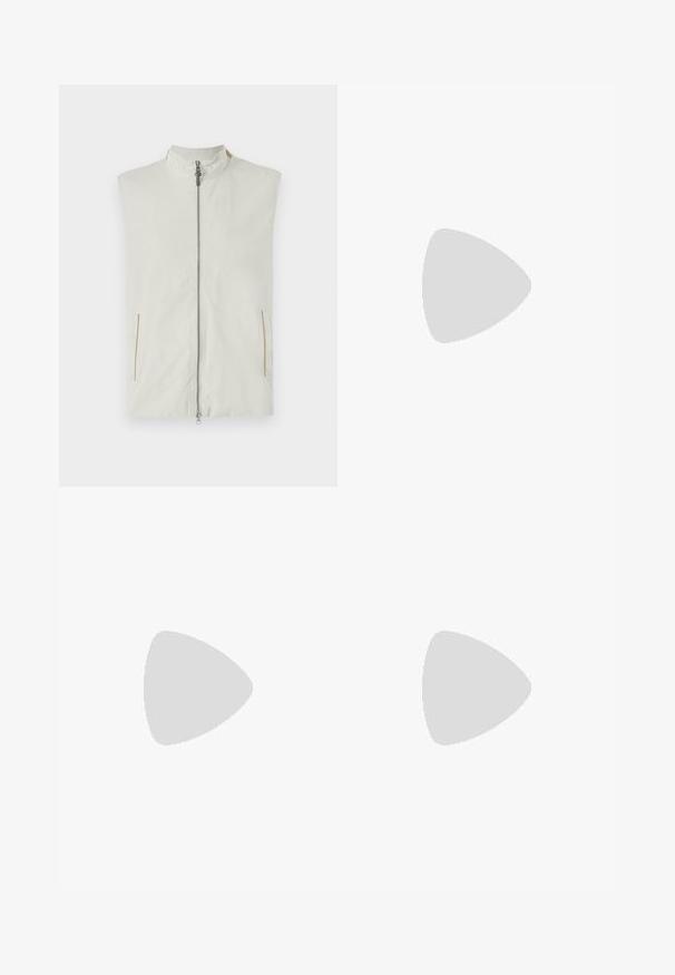 Lichtgewicht mouwloze vest in crème, met een hoge kraag, een rits aan de voorkant en twee zijzakken met subtiele gouden accenten.; Beige T-shirt met korte mouwen en ronde hals, met een klein cartoonachtige patch op de linkerborst waarop een personage met grote ogen te zien is.; Lichtblauwe denim jeans met een recht gesneden ontwerp, vijf zakken en een knoop-rits sluiting. Kenmerkt subtiele vervaging en gestikte details.; Beige lage sneaker met gestructureerde stof, suède details, witte veters, witte hieltab en lichtbruine rubberen zool op een neutrale achtergrond.