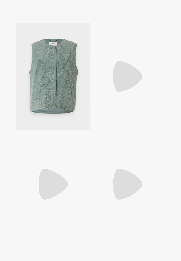 Lysegrøn, ærmeløs vest lavet af struktureret fleece med rund halsudskæring, knaplukning og to sidelommer.; Grøn- og cremefarvet striped, ribbet langærmet trøje med rund halsudskæring og tætsiddende facon, med kontrasterende strikstruktur.; Bredde ben sorte denim jeans med høj talje, der har standardlommer og knaplukning. Glat tekstur med en let stræk.; Sort flad slingback med spids tå og dobbelte spænder, hvilende på grå asfalt nær flisevæg.