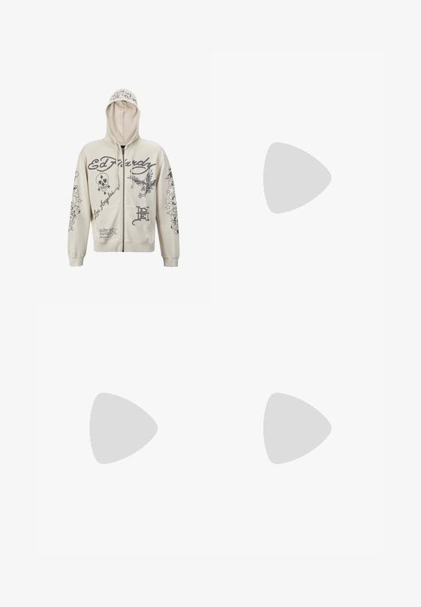 Beige zip-up hoodie met een capuchon. Bevat zwarte grafische ontwerpen, inclusief tekst en illustraties van een schedel en een adelaar. Twee voorzakken.; Zwarte katoenen t-shirt met korte mouwen, ronde hals en een klein geel logo op de linker borst. Eenvoudig ontwerp en normale pasvorm.; Donkerblauwe wijde jeans met een grote witte cartoonhond graphic op de achterzak. Denimtextuur, traditionele vijf-pocket ontwerp.; Zwarte suède sneakers met witte rubberen zolen en zijstrepen, gecombineerd met lichtgroene cargobroeken, staande op een gestructureerd donker oppervlak.