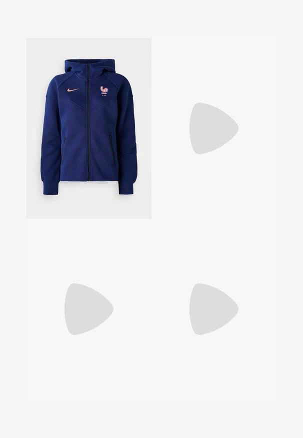 Marineblå hettejakke med glidelås laget av mykt stoff, har kengurulomme, fransk fotballmerke og Nike-logo i korall.; Kortermet T-skjorte med rund hals i taupe, laget av glatt bomull. Har en tettsittende design og fine sømmer langs kanten og ermene.; Brune, vide bukser lavet af slidstærkt stof med knaplukning og sidelommer. Glat tekstur og lige snit.; Hvite og sølv Nike-sneakers med mesh-stoff, reflekterende detaljer, og en beige såle. Brukt med svarte sokker, stående på en blå overflate.