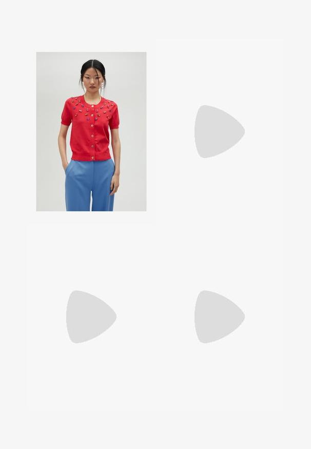 Cardigan court à manches courtes rouge avec des perles décoratives multicolores, col rond et fermeture à boutons ; porté avec un pantalon bleu.; Blouse fleurie à manches bouffantes longues, base crème clair, ornée de motifs floraux violets, oranges et verts, avec un col classique.; Jupe maxi plissée aux couleurs vives de rouge, rose et motif floral marron. La taille élastique et la texture douce améliorent le confort et le style.; Baskets montantes en toile blanche avec semelle en caoutchouc noir, capuchon en caoutchouc à l'avant, et six œillets pour les lacets, présentant un design épuré et minimaliste.