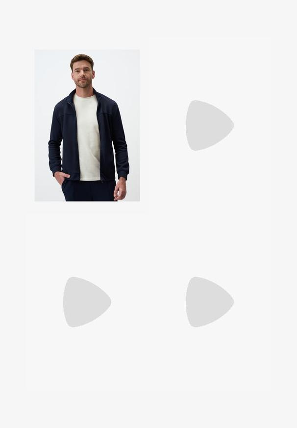 Jimmy Key - Kardigan; Biały bawełniany t-shirt z krótkimi rękawami, okrągłym dekoltem i prostym krojem. Gładka faktura bez widocznych wzorów czy akcentów.; Czarne spodnie o prostym kroju, wykonane z gładkiego materiału. Posiadają zakładki z przodu i pojedyncze zapięcie na guziki w pasie.; Czarne skórzane półbuty z okrągłym noskiem, dekoracyjnym paskiem i elementami metalowymi oraz grubą, fakturowaną podeszwą. Gładkie wykończenie z subtelnymi detalami.