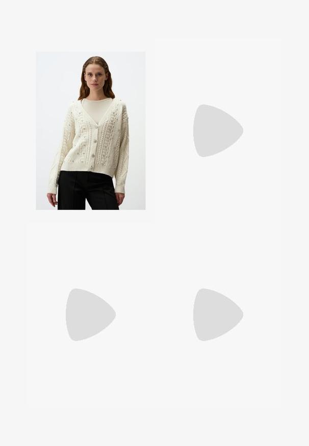 Crème cardigan met een v-hals, ingewikkeld kabelbreisel, versierd met kleine zilveren versieringen en geribde manchetten en zoom.; Lichtroze bloemenjurk met gerimpelde lagen, asymmetrische zoom, dunne bandjes en een klein strikdetail op de rug.; Bershka HIGH-HEEL - Cowboy-/Bikerlaarzen - beige; Rechthoekige zonnebrillen met olijfgroene monturen en donkeroze lenzen. Het ontwerp is slank met rechte armen en zonder zichtbare hardwareaccenten.