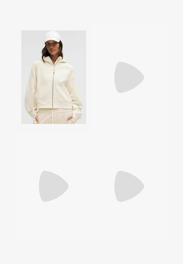 Krémszínű cipzáros kapucnis pulóver, bordázott mandzsettákkal és elülső zsebekkel; puha tapintás és laza fazon kiegészíti a hozzá illő melegítőnadrágot.; Fehér póló, puha, könnyű anyagból készült. Kerek nyakú, rövid, széles ujjaival és laza szabásával rendelkezik. Nincsenek látható minták.; Sötétkék, bőszárú farmernadrág. Erős pamutból készült, magas derékkal, elülső zsebekkel és egyenes, rövidített szegélyekkel, látható varrással.; Fehér hálós sportcipők ezüst részletekkel és texturált talppal, egy piros felületen elhelyezve, kockás nadrággal párosítva.