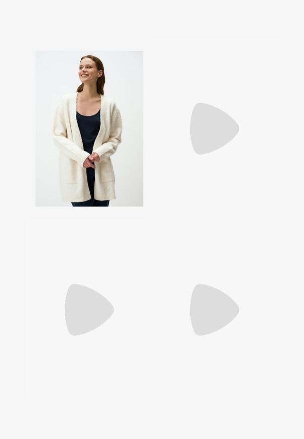 Cardigan bianco e morbido con maniche lunghe, apertura frontale e polsini a coste. Indossato sopra un top scuro, con tasche laterali e texture morbida.; Top corto senza maniche nero realizzato in tessuto liscio, con scollatura rotonda e un design pulito e semplice, privo di pattern o accessori.; Pantaloni neri a gamba dritta, con tasche frontali e spacchi laterali all'orlo. Realizzati in tessuto morbido e liscio. Adatti a diverse occasioni.; Infradito neri con una finitura lucida, tre sottili cinturini e un dettaglio hardware circolare sulla punta. Design elegante con un tacco minimale.