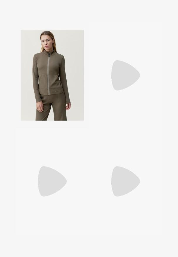 Giacca marrone con zip e colletto alto, texture a coste, vestibilità slim e tasche laterali. Presenta un logo discreto all'orlo e maniche lunghe.; Top bianco aderente realizzato in tessuto a coste, con maniche a farfalla e dettagli arricciati sui lati per texture e forma.; Pantaloni ampi marroni realizzati in un tessuto testurizzato, con vita regolabile e pieghe frontali.; Sandali con tacco trasparente caratterizzati da due cinturini trasparenti, una base beige e un tacco a blocco trasparente geometrico. Design minimalista con texture liscia.