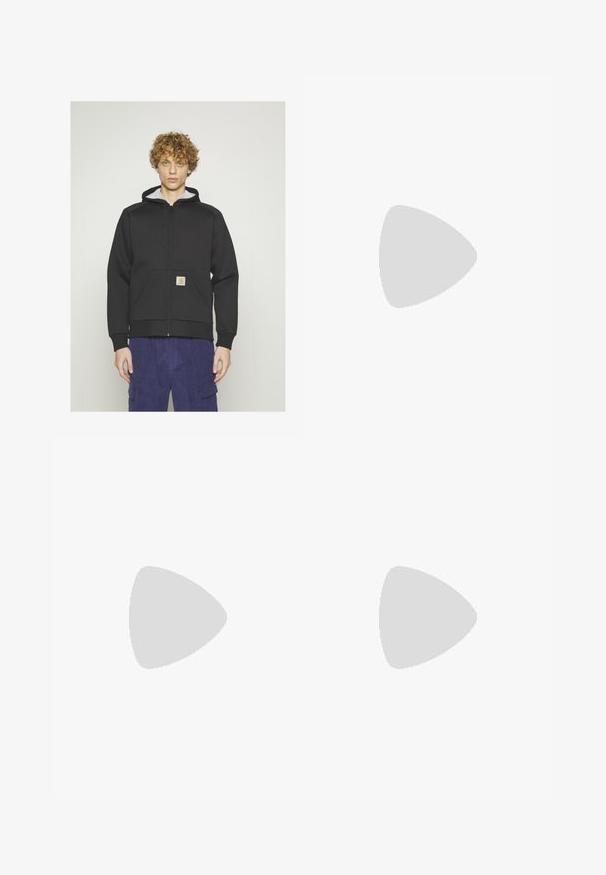 Carhartt WIP - Bluza rozpinana; T-shirt z krótkim rękawem w kolorze turkusowym, okrągły dekolt i małe białe logo na górnej lewej części klatki piersiowej. Gładka tekstura, luźny krój.; Czarne dżinsy o luźnym kroju, z kontrastującymi białymi szwami, z zapięciem na guzik i prostą nogawką.; Zielone zamszowe sneakersy z białymi paskami, teksturowanymi sznurówkami i brązową gumową podeszwą. Połączone z beżowymi spodniami, na tle niebieskiego dywanu.