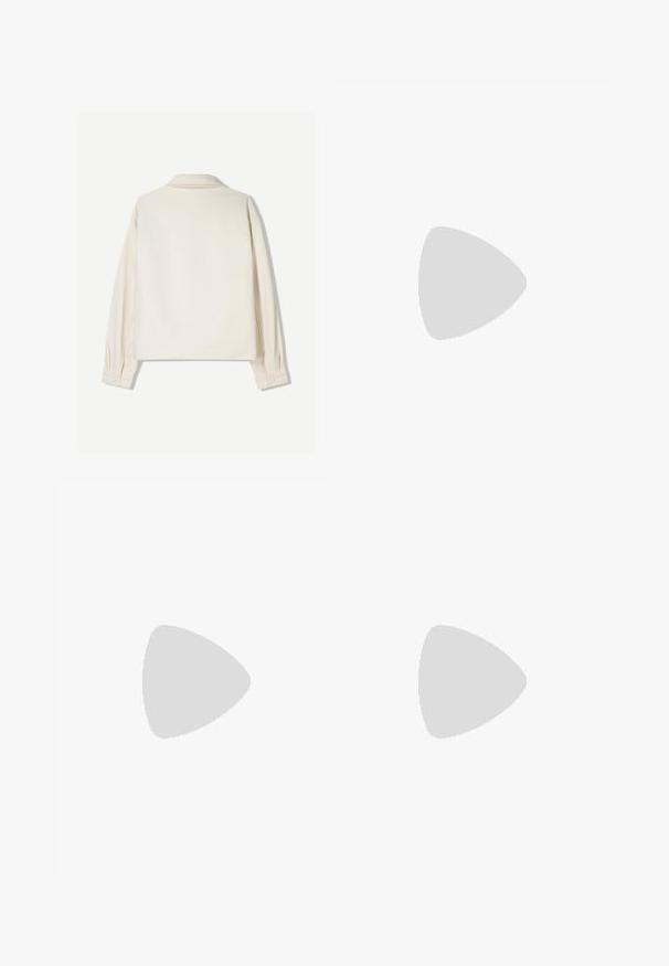 Kremowa kurtka z wyraźnym kołnierzem, długimi rękawami i zapięciami na guziki. Wykonana z teksturowanej tkaniny o prostym kroju i minimalnych detalach.; Niebieska koszulka polo wykonana z miękkiego materiału. Posiada klasyczny kołnierzyk, zapięcie na trzy guziki oraz małe logo na klatce piersiowej.; Beżowe spodnie szerokie wykonane z mocnej tkaniny, z wysokim stanem, widocznym szwem i małą naszywką z logo z boku.; Białe sportowe buty z siateczki z srebrnymi akcentami, wyposażone w grubą podeszwę i system sznurowania. Noszone z szarymi spodniami sztruksowymi. Niebieskie tło dywanu.