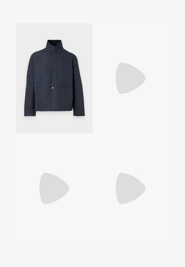 Marineblauwe waterdichte jas met een hoge kraag, drukknoopsluiting en twee voorzakken. Gemaakt van stevige stof met een gladde textuur.; Witte T-shirt met korte mouwen met rode tekst "Studio Originals Edition" op de linker borst, weergegeven op een neutrale grijze achtergrond.; Twee paren opgerolde shorts: een beige en een zwarte, gemaakt van gladde stof, met een frontknop en een klassiek ontwerp.; Witte instap sneakers met een gestructureerd oppervlak, een dikke zool en een minimalistisch ontwerp. Bevat het merklogo aan de zijkant.