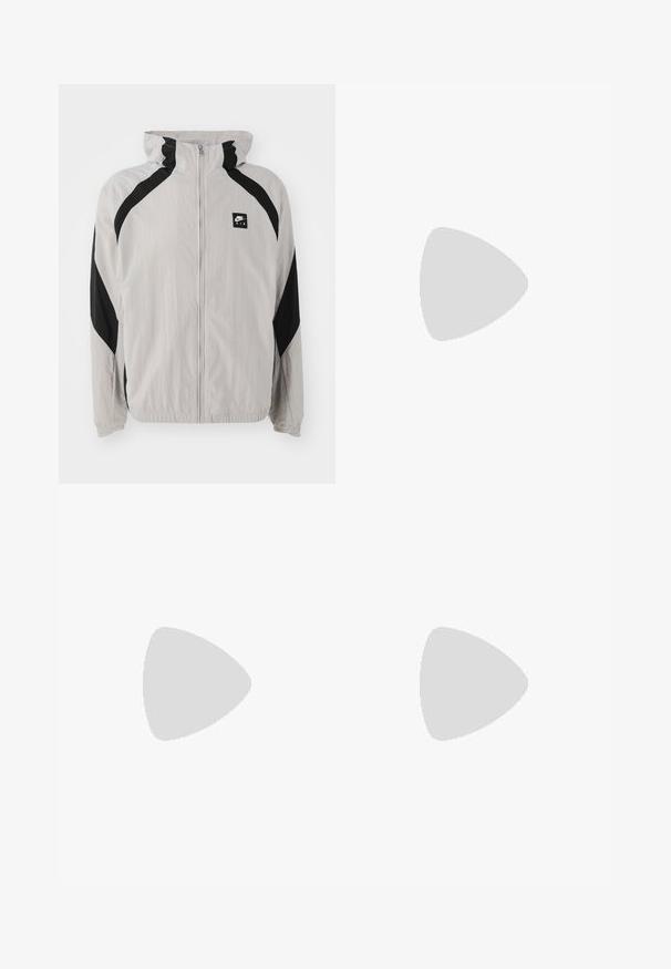 Light gray windbreaker jacket with black accents, zipper closure, and hood. Features a Nike logo and elastic cuffs at the sleeves.; Beige cotton t-shirt with a soft texture, featuring a straight hem and two visible labels stitched at the bottom, marked "DEF."; Black lightweight cargo pants with an elastic waistband, side zippers, and spacious pockets. Features a loose fit and tapered cuffs.; White athletic shoes with textured overlays, a chunky sole, and gray accents. Worn with white crew socks and green shorts on a blue surface.
