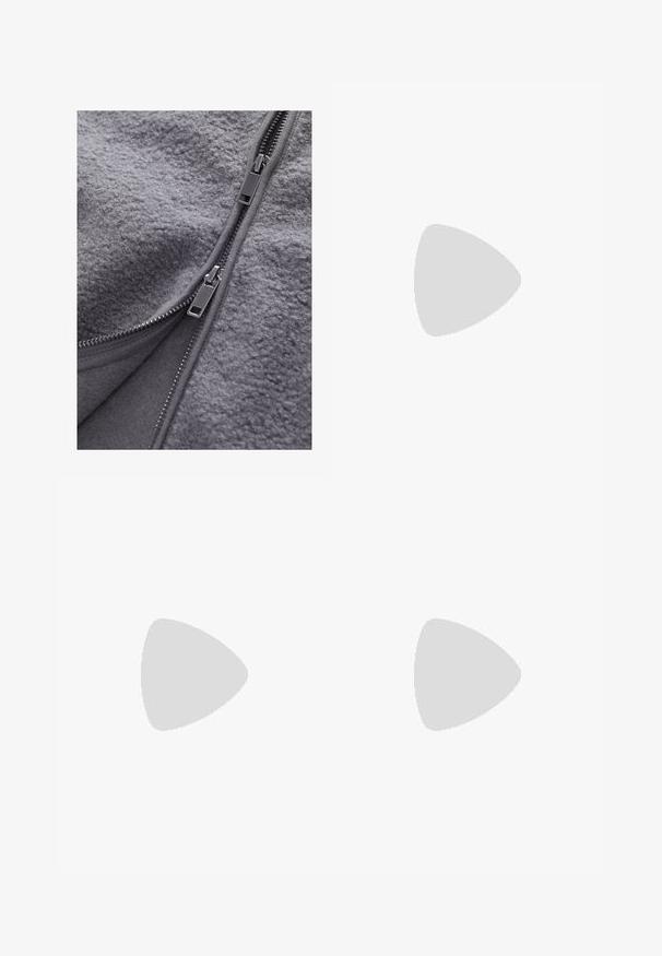 Tejido de forro polar gris con una textura suave y cremalleras a lo largo de la apertura. Las cremalleras cuentan con tiradores metálicos en los bordes para mayor funcionalidad.; Camiseta de algodón blanca de manga corta, cuello redondo y un corte relajado. Textura suave y sin patrones ni acentos visibles.; Jeans de mezclilla azul con un corte recto, que presentan un cierre de botón, diseño de cinco bolsillos y un desvanecimiento sutil para agregar textura.; Zapatilla deportiva New Balance con parte superior de malla, predominantemente blanca con acentos en gris y azul marino, que presenta una suela acolchada y detalles texturizados.