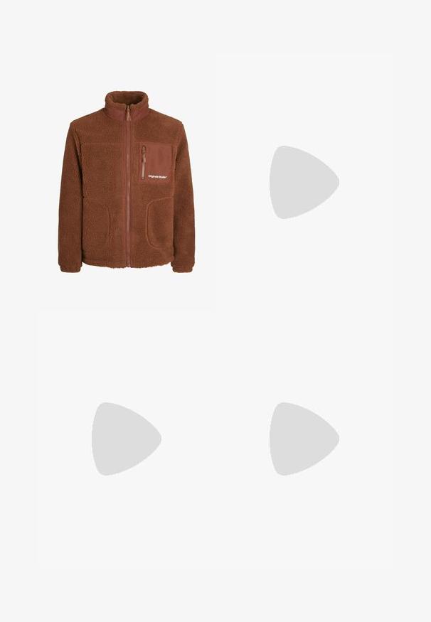 Jachetă din fleecă maro cu guler înalt, fermoar frontal, două buzunare laterale și un buzunar pe piept. Are o textură moale și detalii cu logo.; Cămașă albă cu mânecă lungă, realizată din bumbac fin, având un guler clasic și închidere cu nasturi în față, fără motive sau accente.; Pantaloni de culoare ruginită, cu o textură estompată, având două petice mari, decupate și tocite pe genunchi și buzunare standard.; Picioare încălțate cu adidași Adidas bej țesuți, cu talpa din cauciuc natural, și ciorapi albi până la gleznă, pe o podea verde texturată.