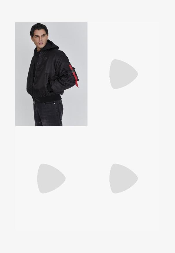 Man i svart bomberjacka med röd remdetalj på ärmen och svart hoodie, som tittar åt vänster mot en enfärgad grå bakgrund.; Ung person med flätat hår iklädd en ljusgrå Nike T-shirt och svarta Nike-shorts framför en enkel vit bakgrund.; Beiga cargobyxor i ett lätt bomullsmaterial. Har elastiska mudd, flera sidofickor och en knappstängning.; Vita lädersneakers med perforeringar, rund tå, platt sula och tjocka snörning, med en synlig swoosh-logga och "AIR" på hälen.