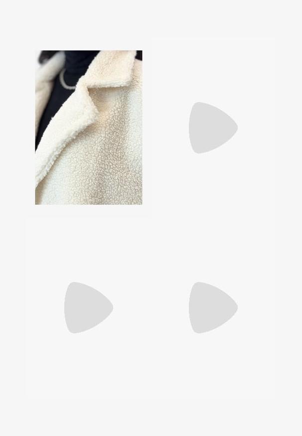 Cremefarvet falsk shearling-frakke med klapkrave, der har en blød, struktureret overflade og minimal syning, lagd over en sort bluse.; Afskåret, lysegrå striktrøje med højt krave og ribbede manchetter, prydet med teksturerede kabelmønstre ned ad ryggen og siderne.; Bredde ben-bukser i en lys beige farve, lavet af et glat stof. Har en klassisk talje og flad front med rene linjer.; Brune ruskinds Chelsea støvler med elastiske sidepaneler og en tyk, struktureret platåsål. Har en strop bagpå til nem påtagning.