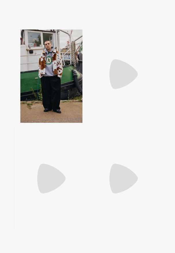 Un tânăr îmbrăcat cu o haină de blană maro cu pete albe deasupra unui hanorac Oakland Athletics stă pe malul apei lângă o barcă verde.; Tricou negru din bumbac, cu text mare și texturat "FAVELA" pe față. Mâneci scurte, croială lejeră, decolteu rotund, design minimal.; Pantaloni negri din bumbac cu croială lejeră, având un brâu clasic, plii frontale și buzunare laterale. Textură netedă fără modele.; Adidași negri din suede cu talpă din cauciuc albă, cu un design cu șireturi, accente texturate și branding subtil, asortați cu pantaloni maro.