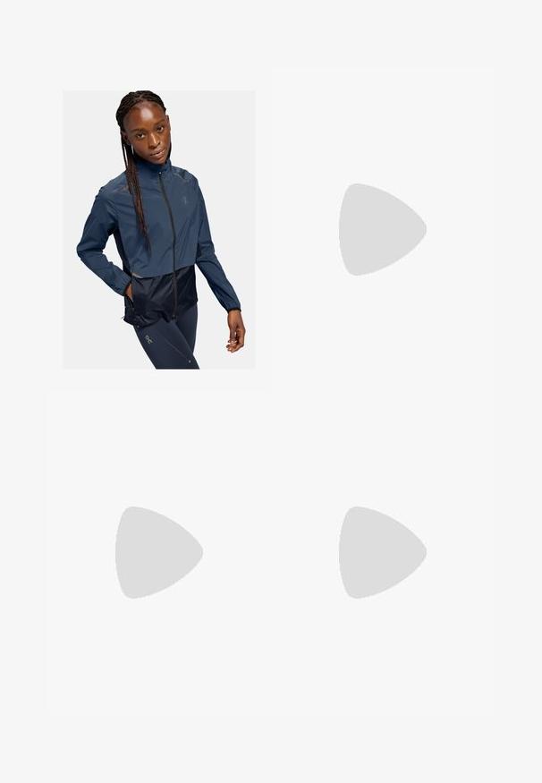 Marineblå vindjakke med et cropped design, der har lynlåslukning, lange ærmer og reflekterende detaljer. Materialet ser glat og letvægtigt ud.; Langærmet lysegrøn skjorte lavet af tekstureret stof, med en rund halsudskæring og et lille logo på venstre bryst.; Lys grønne atletiske shorts lavet af åndbart stof, med perforeret tekstur og elastisk talje. Logo trykt på siden.; Lysende neongrøn New Balance løbesko hviler på struktureret asfalt nær en taktil gangflade og kantstenen.; Beige canvas indkøbstaske med to sorte trykte "SAMØE" logoer. Har holdbare beige skulderremme og et simpelt, ustruktureret design.