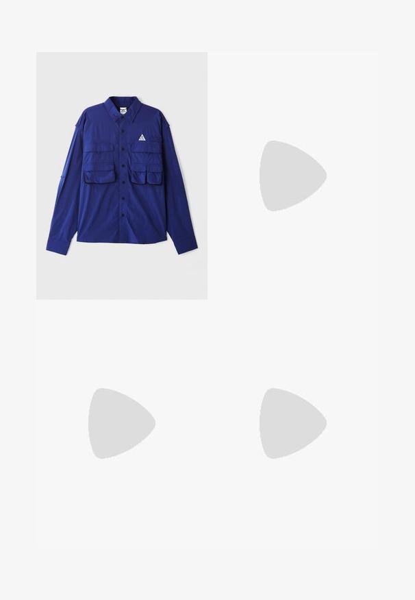 Blue long-sleeve shirt with two chest pockets, button-up front, and a triangular logo on the left side. Made from lightweight fabric.; Green hoodie made of soft fabric, featuring a kangaroo pocket, drawstrings, and a small white Nike logo on the left chest.; Black sweatpants made of soft material with an elastic waistband, drawstring, and tapered cuffs, featuring a subtle logo on the side.; White athletic shoes with textured overlays, a chunky sole, and gray accents. Worn with white crew socks and green shorts on a blue surface.