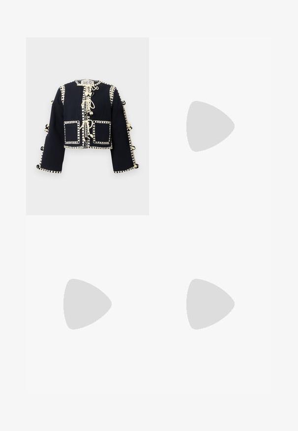 Svart långärmad korthamad jacka med krämfärgad dekorativ sömnad, framfickor och pom-pom snörning längs mitten och ärmarna.; Vit bomull t-shirt med kort ärm, rund halsringning, avslappnad passform och söm i nederkant. Etikett synlig på insidan av halsen.; Beige linnebyxor med lös passform, veckad front och raka ben. Har ett midjeband med bältesöglor och inga synliga fickor.; Svart läder ankelboot med spetsig tå och en smidig design. Har en låg klack och en dragkedjestängning bak. Slät textur.