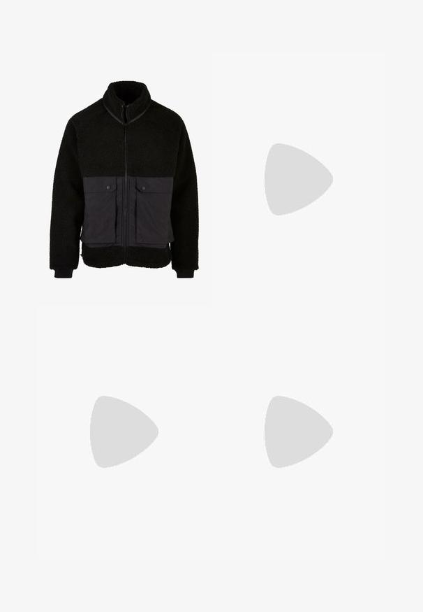 Čierna flísová bunda s textúrovanou hornou časťou a hladkým spodným materiálom. Obsahuje vysoký golier, predný zips a dve vrecká na hrudi so zapínaním na patentky.; Mladý človek s vrkôčikmi, oblečený v svetlošedé tričko Nike a čierne šortky Nike, na pozadí bielej steny.; Béžové cargo nohavice vyrobené z ľahkej bavlny. Majú elastické manžety, viacero bočných vreciek a zapínanie na gombík.; Biele kožené tenisky s perforáciami, okrúhlou špičkou, plochou podrážkou a hrubými šnúrkami, pričom majú viditeľné logo swoosh a nápis "AIR" na päte.