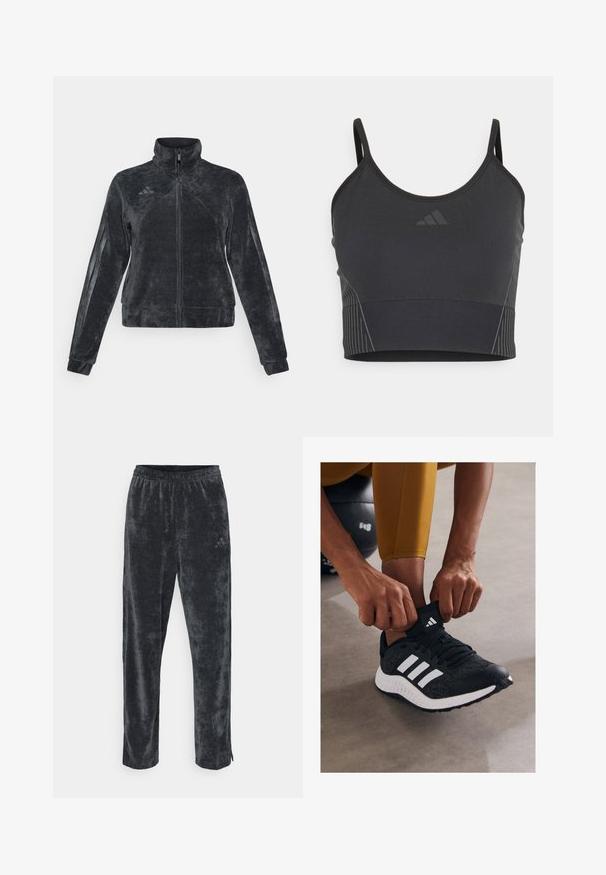 Chaqueta de forro polar negra con cuello alto, cierre de cremallera y franjas laterales. Presenta un tejido texturizado y el logo de Adidas en la parte superior izquierda.; Top corto atlético negro con tirantes finos, hecho de material elástico, que presenta acentos de rayas tonales y un pequeño logo en la parte delantera.; Pantalones de terciopelo gris suave con un ajuste relajado, que cuentan con una cintura elástica y rayas laterales sutiles. Pequeño acento de logo en la parte superior de la pierna.; Zapato deportivo negro con rayas blancas, parte superior texturizada y suela de goma. La persona está ajustando el collar del calcetín mientras está sentada sobre una superficie gris.