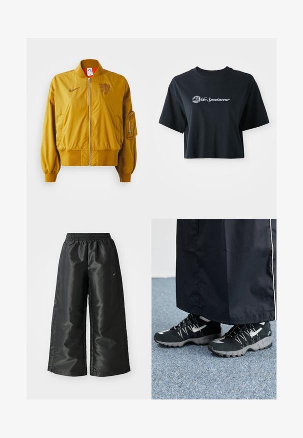 Gele bomberjack met elastische manchetten en zoom, voorzien van een voorrits, zijzakken en een logo-detail op de borst.; Korte zwarte katoenen t-shirt met korte mouwen, voorzien van witte tekst "Vice Sportswear" en een ronde afbeelding aan de voorkant.; Zwarte sportbroek van een glanzende, gladde stof, met een elastische tailleband, wijde pijpen en een klein logo aan de linkerkant.; Zwarte atletische schoenen met een gestructureerde bovenkant, zilveren accenten en een gestippelde loopzool, gecombineerd met een zwart lang kledingstuk. Geplaatst op een blauwe vloerbedekking.