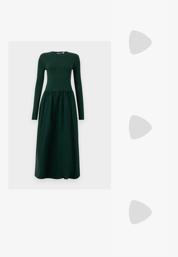 Long-sleeve, dark green dress with a fitted top and flowy, gathered skirt. Made from soft fabric with a round neckline and ankle length.; White leather sneakers, low-top design, featuring a smooth texture, round toe, laced front, and a small embroidered logo on the side.; Black leather half-moon bag with a gold hardware accent, featuring a zip closure. Worn crossbody over a gray sweater.; Gold-tone knot stud earrings with a twisted design. Each earring features a circular clear backing for secure wear.