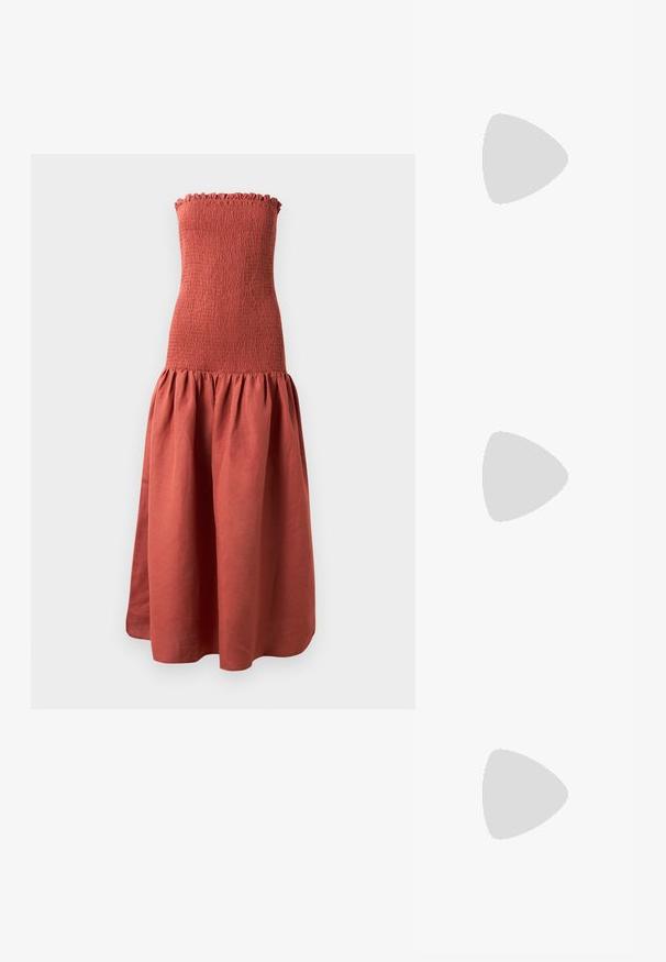 Vestido largo sin tirantes con un corpiño fruncido en color óxido, que presenta una falda acampanada y recogida para un aspecto texturizado.; Zapatillas de cuero blancas, diseño de corte bajo, con una textura suave, puntera redonda, cordones en la parte delantera y un pequeño logo bordado en el lateral.; Bolso negro de cuero en forma de media luna con un acento de hardware dorado, con cierre de cremallera. Llevado cruzado sobre un suéter gris.; Pendientes de botón en tono dorado con un diseño retorcido. Cada pendiente cuenta con un respaldo circular transparente para una sujeción segura.