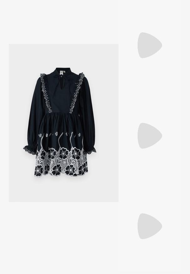 Crna haljina s dugim rukavima, ruffles dekolteom, prorezom sprijeda i bijelom cvjetnom izvezenom dekoracijom na rubu i ramenima.; Crne lakirane slingback visoke potpetice s šiljastim vrhom, zaobljenim izrezom i blok potpeticom. Sadrži akcent zlatnog tona s kopčom.; Crne prevelike sunčane naočale s gradijentnim lećama, debelim okvirom i zlatnim lancem kao detaljem na krakovima.; Crna torba s oblikom koji sadrži strukturu, glađu teksturu i metalnu kopču. Uparena s širokim crnim hlačama i sandalama na otvorenom s drvenog poda.