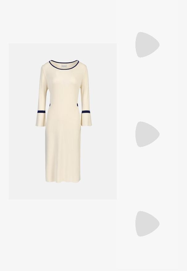 Crème gebreide jurk met driekwart klokmouwen, voorzien van marineblauwe accenten bij de halslijn en manchetten, en zijzakken. Eenvoudig, aansluitend ontwerp.; Zwarte gepolijste leren slingback hakken met een spitse neus, een ronde uitsnede en een blokhak. Voorzien van een gouden gespaccent.; Zwarte oversized zonnebril met gradient glazen, dikke montuur en gouden kettingdetails op de pootjes.; Zwarte tote bag van synthetisch materiaal, met een eenvoudig rechthoekig ontwerp, gouden vierkante accenten en dubbele handvatten.