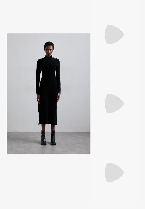 Black long-sleeve dress in a textured fabric with a high collar and silver accent at the shoulder, paired with black ankle boots.; Black leather slingback shoe with a pointed toe, slim high heel, and a decorative bow accent. Smooth texture and sleek design.; Silver metallic shoulder bag with a smooth texture, curved design, chain strap, and a polished front panel featuring a subtle logo engraving.; Silver earrings with a flowing, spiral design. Smooth texture with a polished finish. Features a subtle sheen and no visible embellishments.