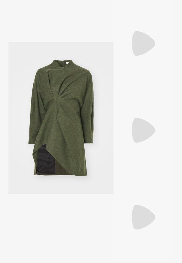 Vestido de mezcla de lana verde con un cuello alto, dobladillo asimétrico y detalle retorcido en la cintura; cuenta con un forro interior negro.; Sandalias metálicas plateadas con diseño de tira entre los dedos, correa al tobillo y suela plana con un acabado texturizado.; Bolso de mano de piel negra con cadena en tono dorado y acento de logotipo. Presenta una forma rectangular con solapa plegable. Textura suave.; Anillo en forma de corazón con superficie de esmalte negro y borde dorado, llevado en una mano contra un fondo de tela marrón texturizada.