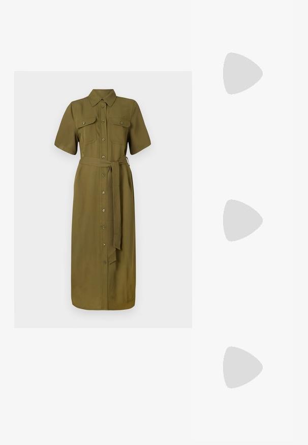 Abito camicia color khaki, maniche corte, con bottoni frontali, due tasche sul petto, vita con cintura, lunghezza media, tessuto dalla texture morbida.; Sneakers in pelle bianca, design low-top, caratterizzati da una texture liscia, punta rotonda, chiusura con lacci e un piccolo logo ricamato sul lato.; Borsa a mezzaluna nera in pelle con dettagli in hardware dorato, dotata di chiusura con zip. Indossata a tracolla sopra un maglione grigio.; Orecchini a perno in tono oro con design intrecciato. Ogni orecchino presenta uno sfondo circolare trasparente per una vestibilità sicura.