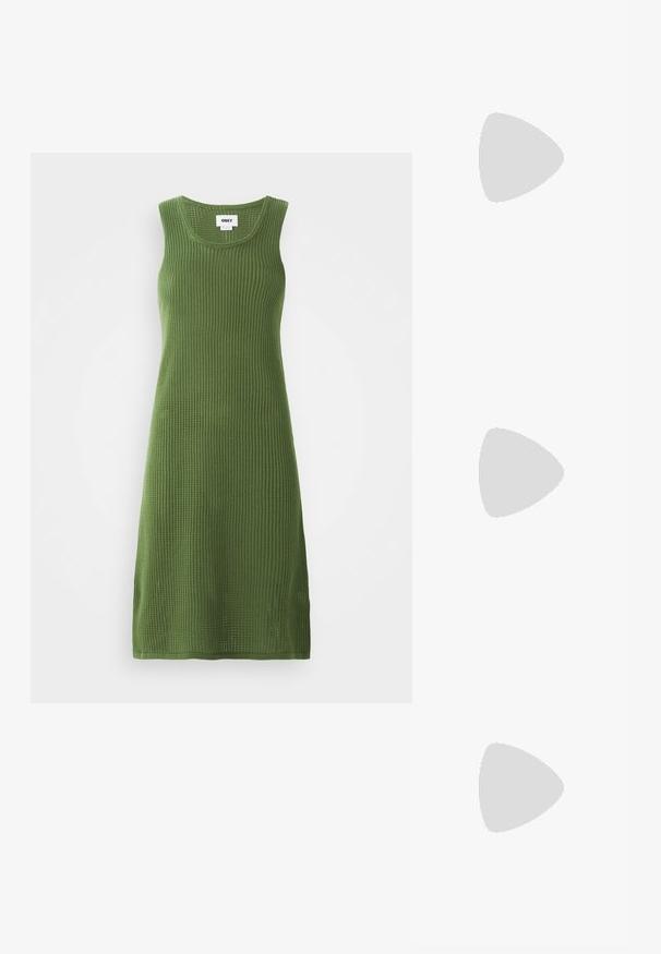 Vestito a maglia senza maniche di colore verde oliva con una texture a coste, caratterizzato da un scollo rotondo e spacchi laterali per facilitare il movimento.; Sandali con tacco in vernice nera, con punta squadrata, cinturini alla caviglia e fibbie in argento. Presentano un tacco a blocco spesso per maggiore stabilità.; Occhiali cat-eye in acetato trasparente con lenti gialle, indossati da una persona con giacca di pelle nera e dolcevita rossa. Texture liscia.; Borsa a tracolla nera in pelle con una forma curva, manico rimovibile e accessori dorati. La borsa presenta una patta con un dettaglio a fibbia.