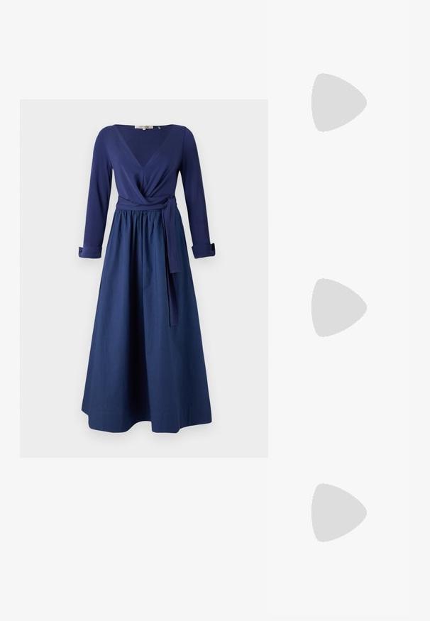 Tengerészkék ruha hosszú ujjal, V-kivágással, áttakaro dizájnal és övvel ellátott derékkal. Hosszú szoknya sima textúrával.; Fekete magassarkú szandál, sima bőrből készült felsőrésszel, nyitott orral és egyetlen pántos dizájnnal, arany csattal díszítve.; Fekete bőr táska strukturált dizájnnal, cipzáras záródással, levehető pánttal és arany színű kiegészítőkkel.; Arany színű csomó fülbevalók, csavart formával. Minden fülbevaló mögött egy kör alakú átlátszó támasz található a biztonságos viselés érdekében.